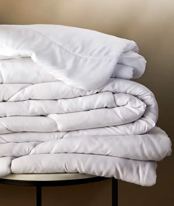 Assorted folded duvets stacked on a table