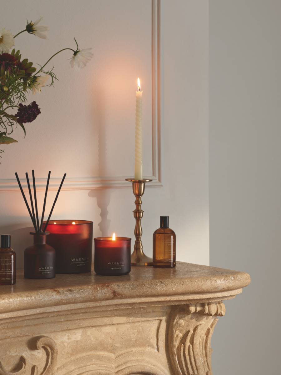 Candles, candle holders and reed diffusers on a fireplace