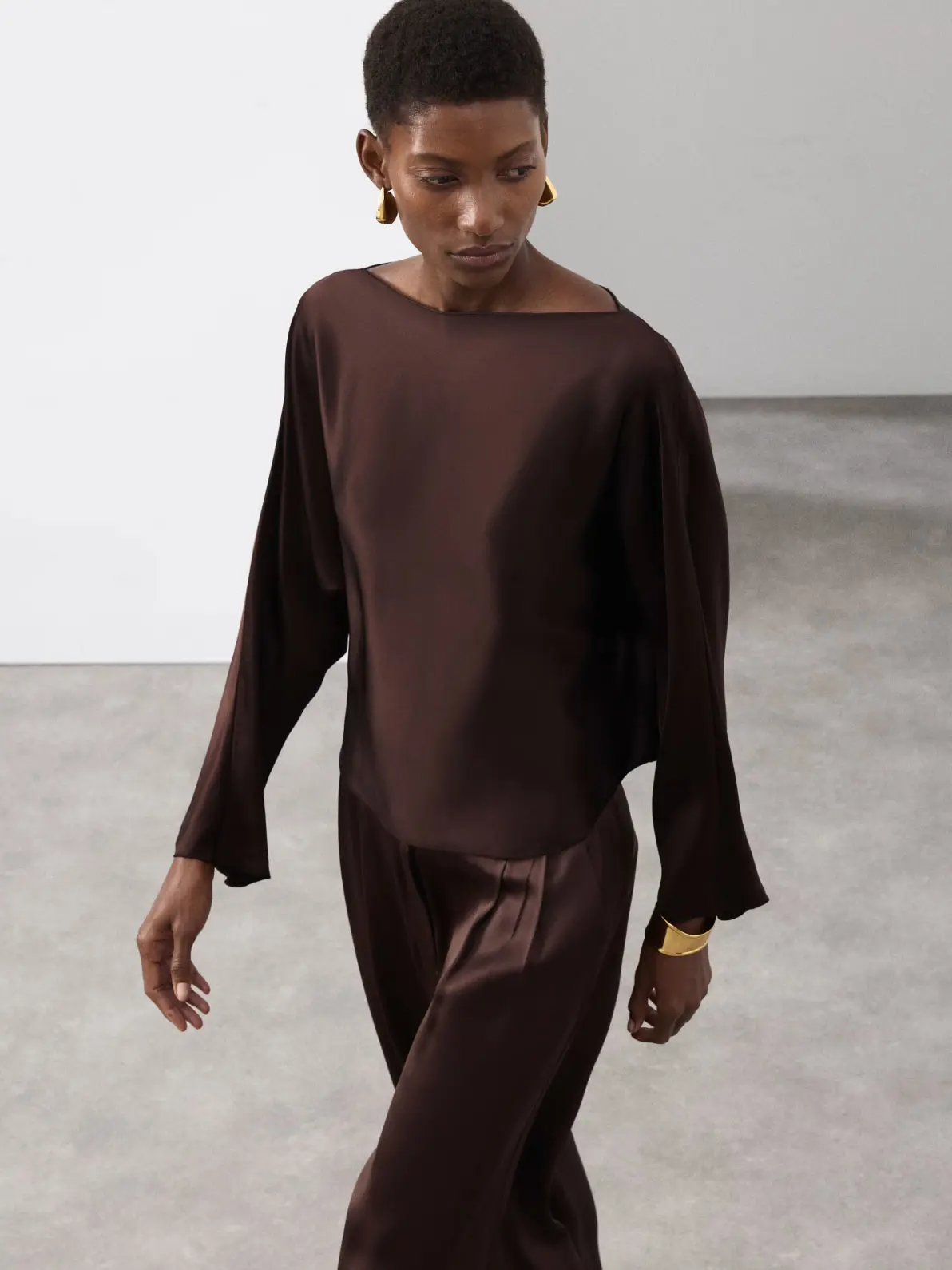 Woman wearing brown top and brown satin trousers