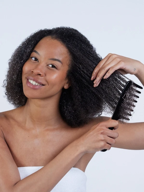 Woman brushing hair with wide tooth comb