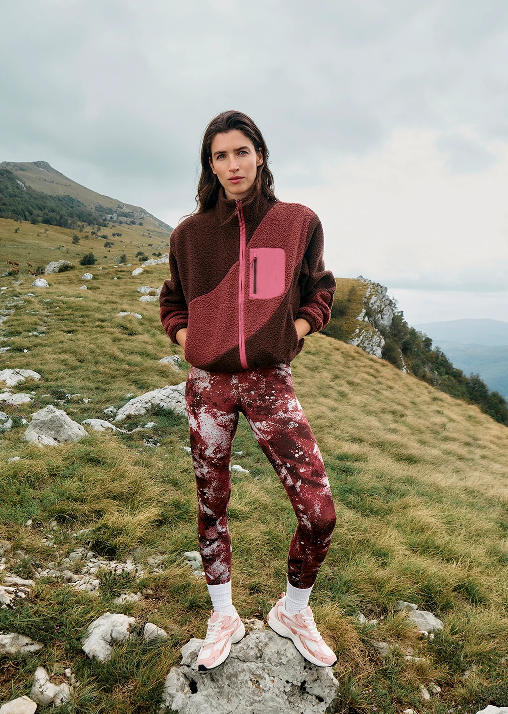 Woman wearing pink fleece. pink patterened leggings and light pink trainers