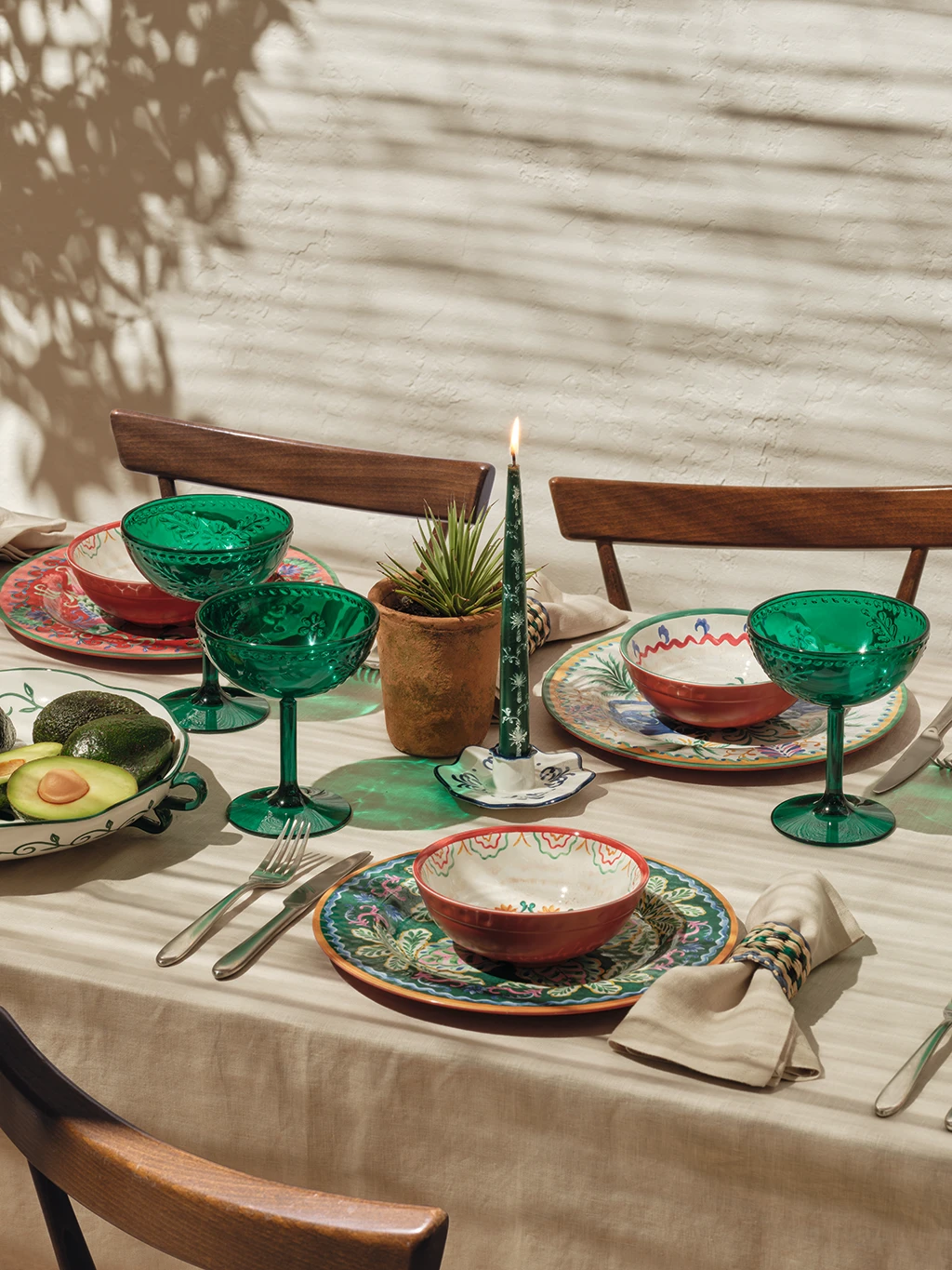 Garden party scene featuring colourful crockery, pillar candles and bowls of fruit