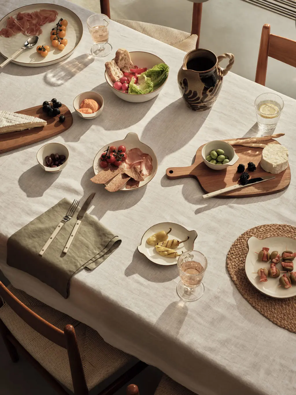 Garden party scene featuring wooden crockery, neutral ceramics and bowls of picky bits