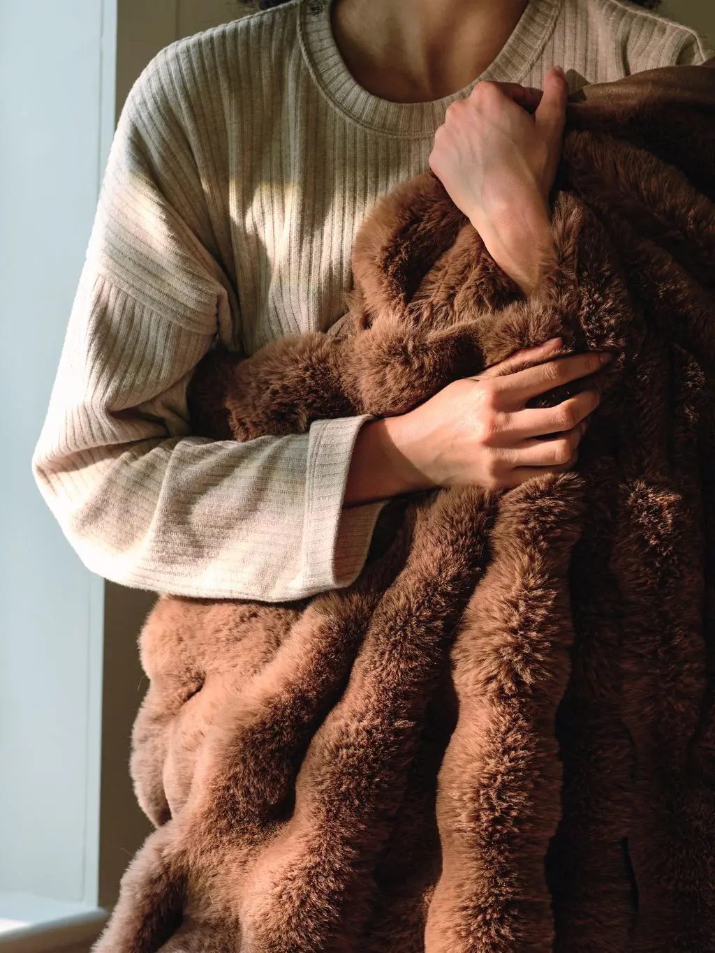 A woman cuddling a cosy brown throw