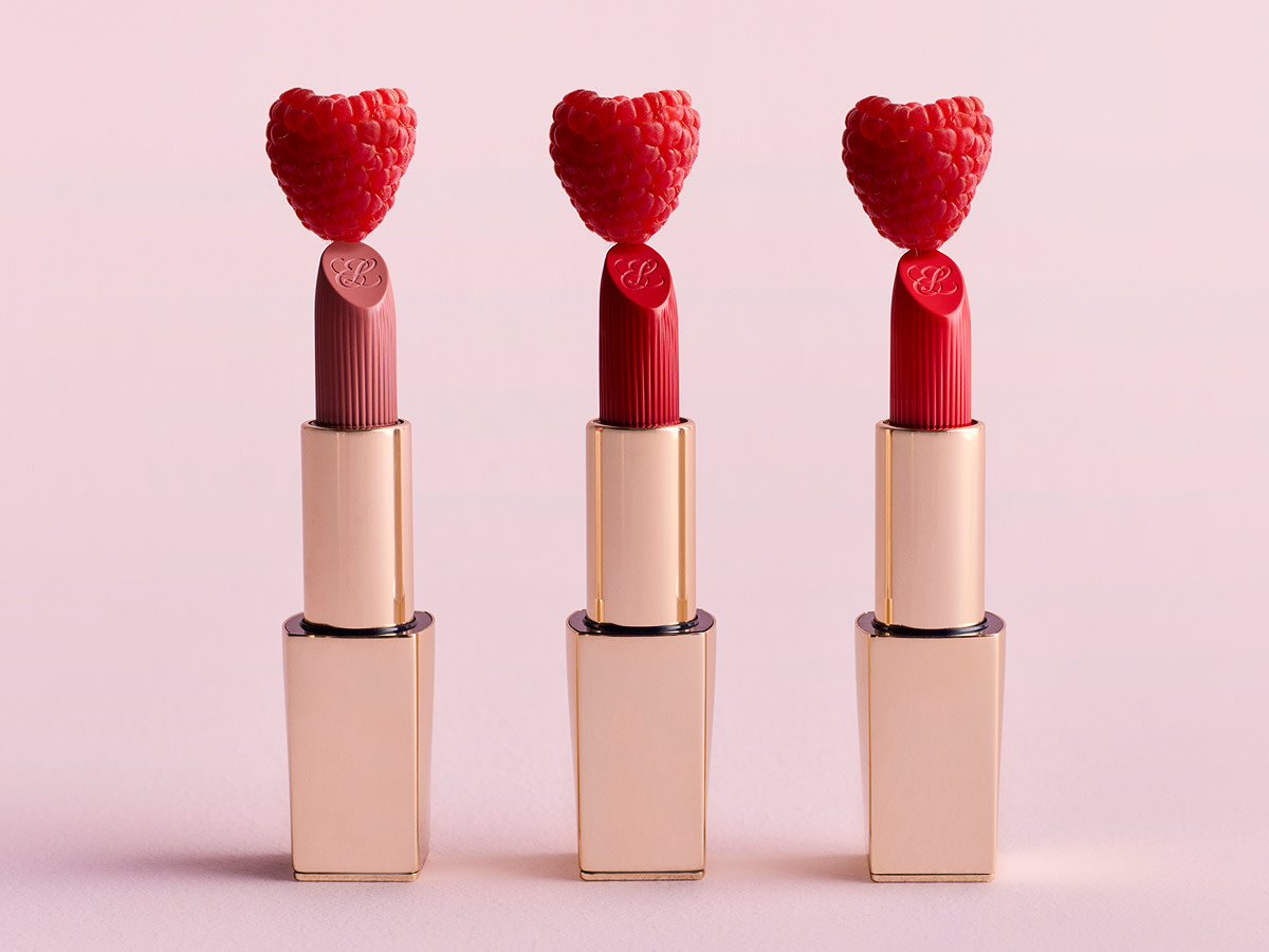 Three red lipsticks against pink background