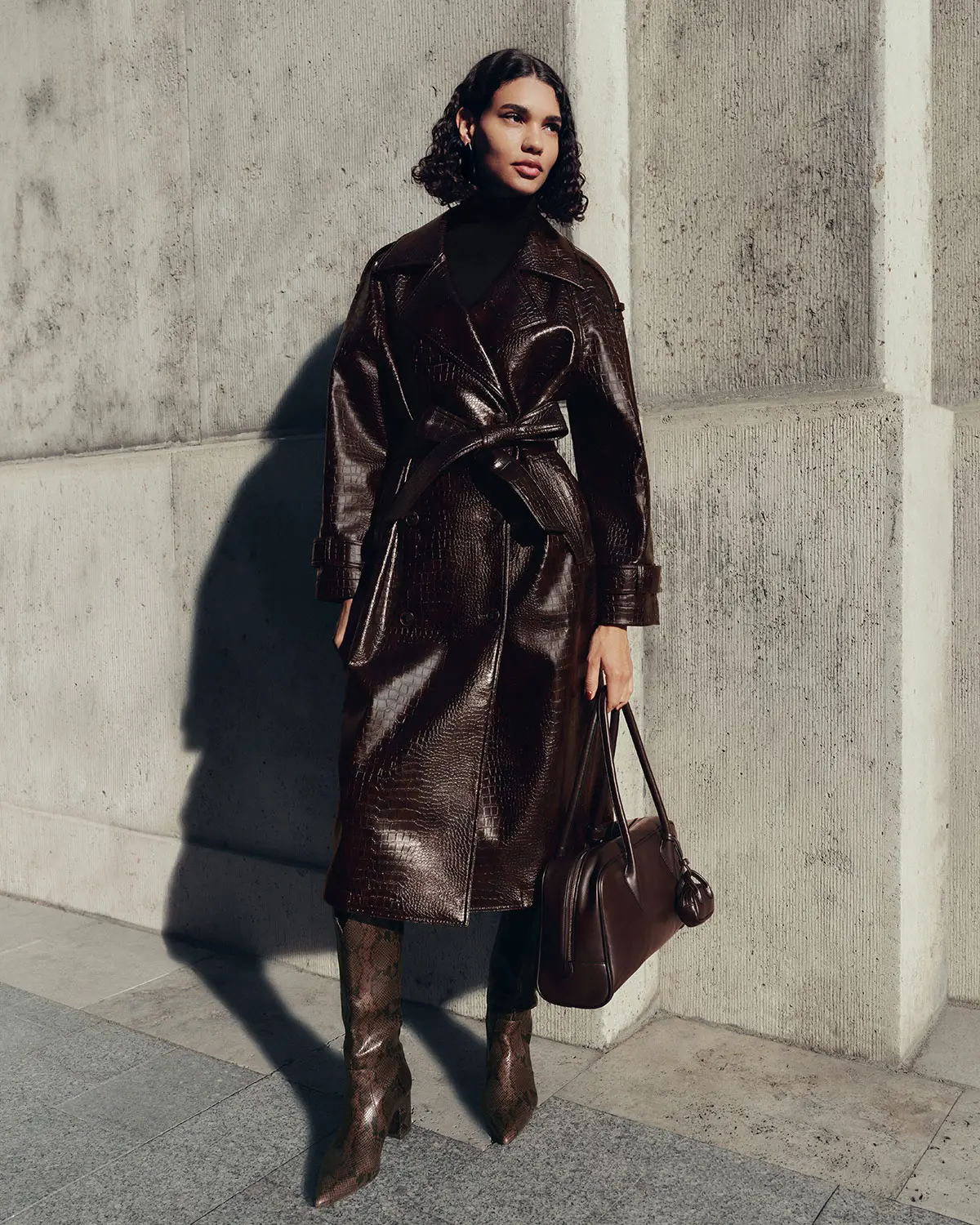 Woman wearing brown mock croc coat, brown snakeskin-effect boots and a brown bag