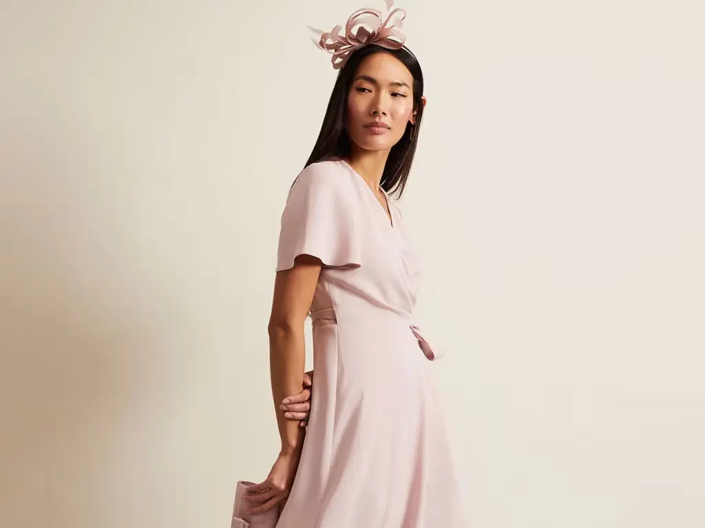 Woman wearing pale pink dress and fascinator by Phase Eight at M&S