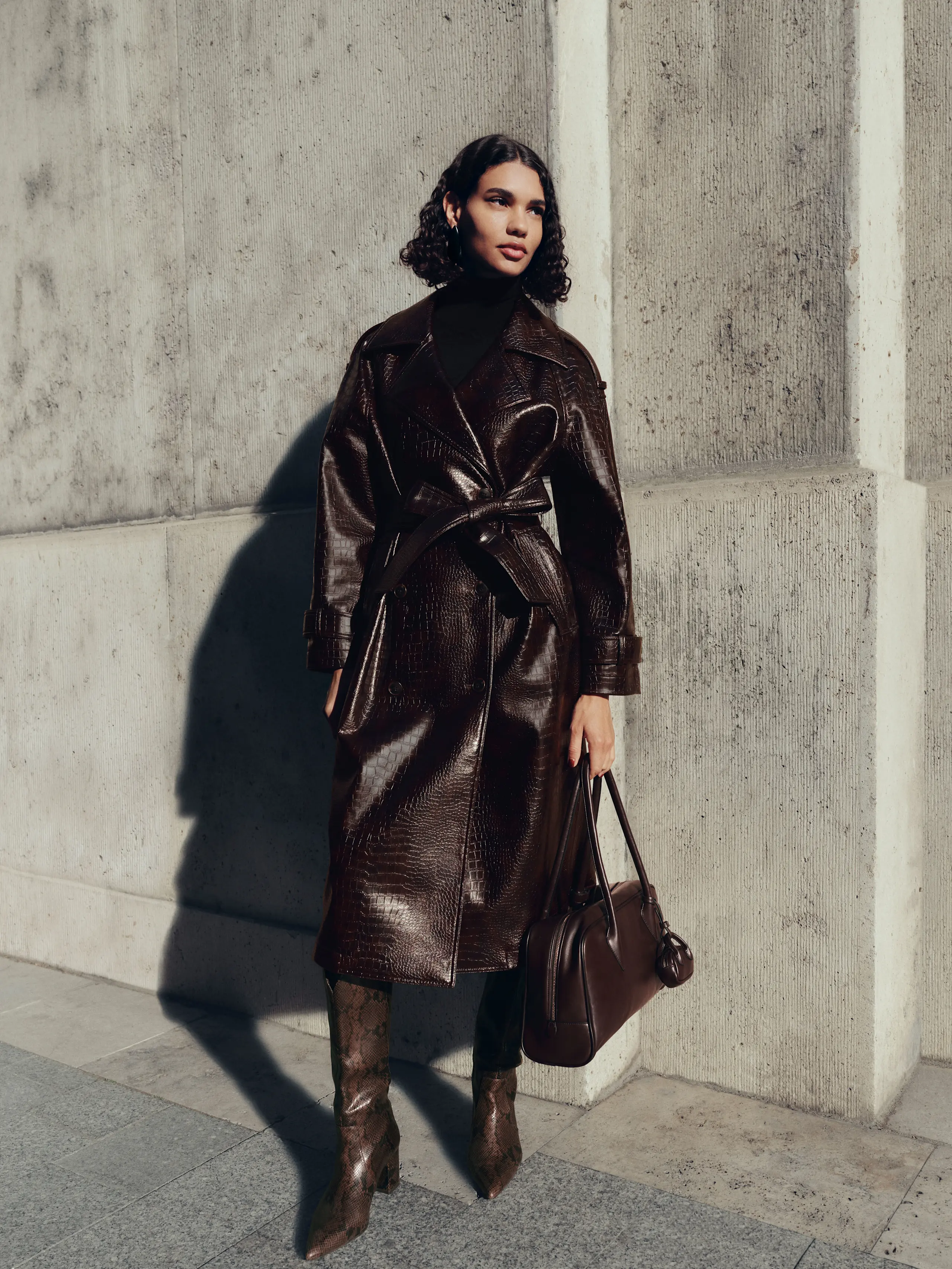 Woman wearing chocolate brown leather coat, bag and long boots
