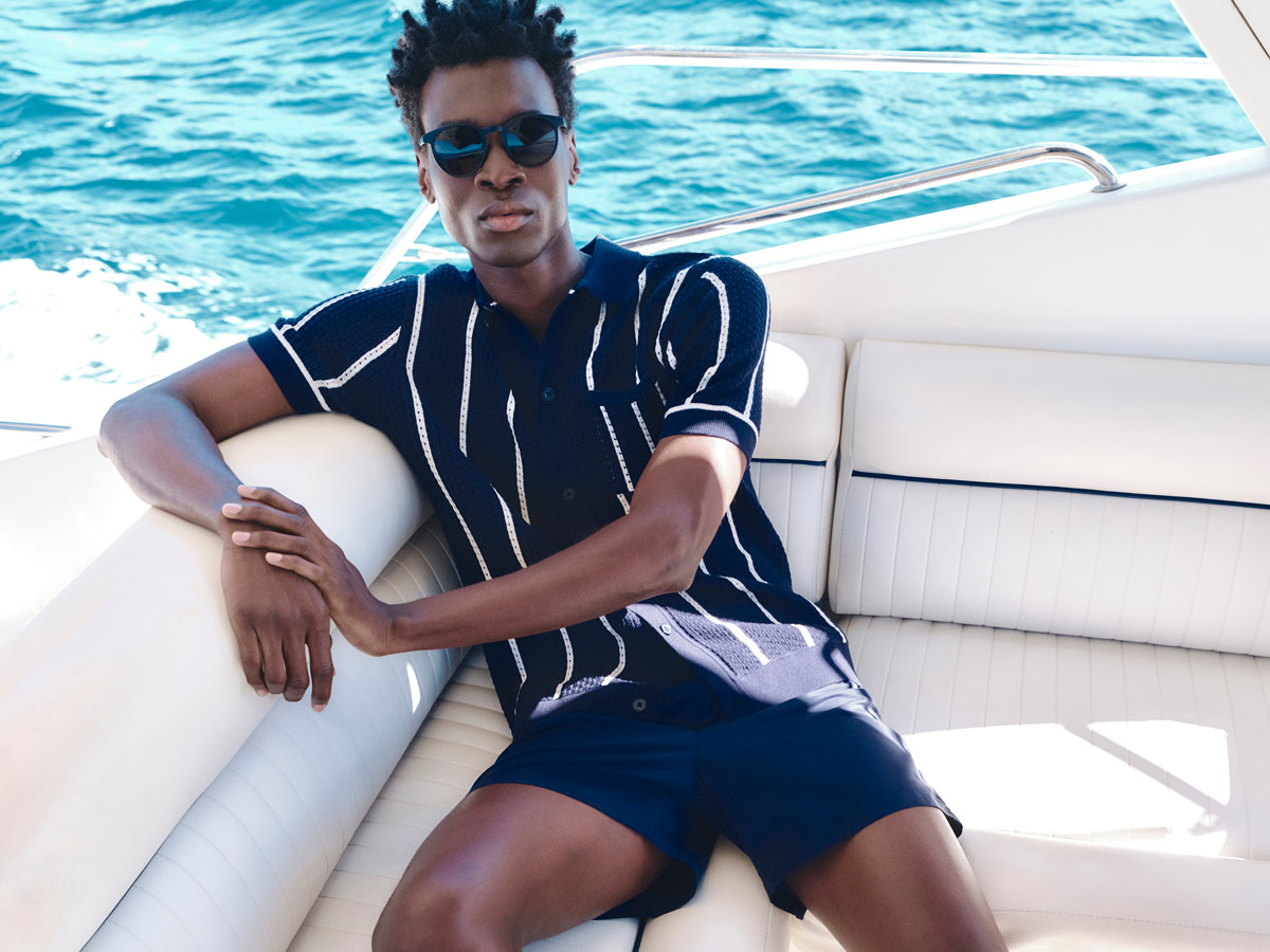 Man wearing navy shorts and a striped top on a boat