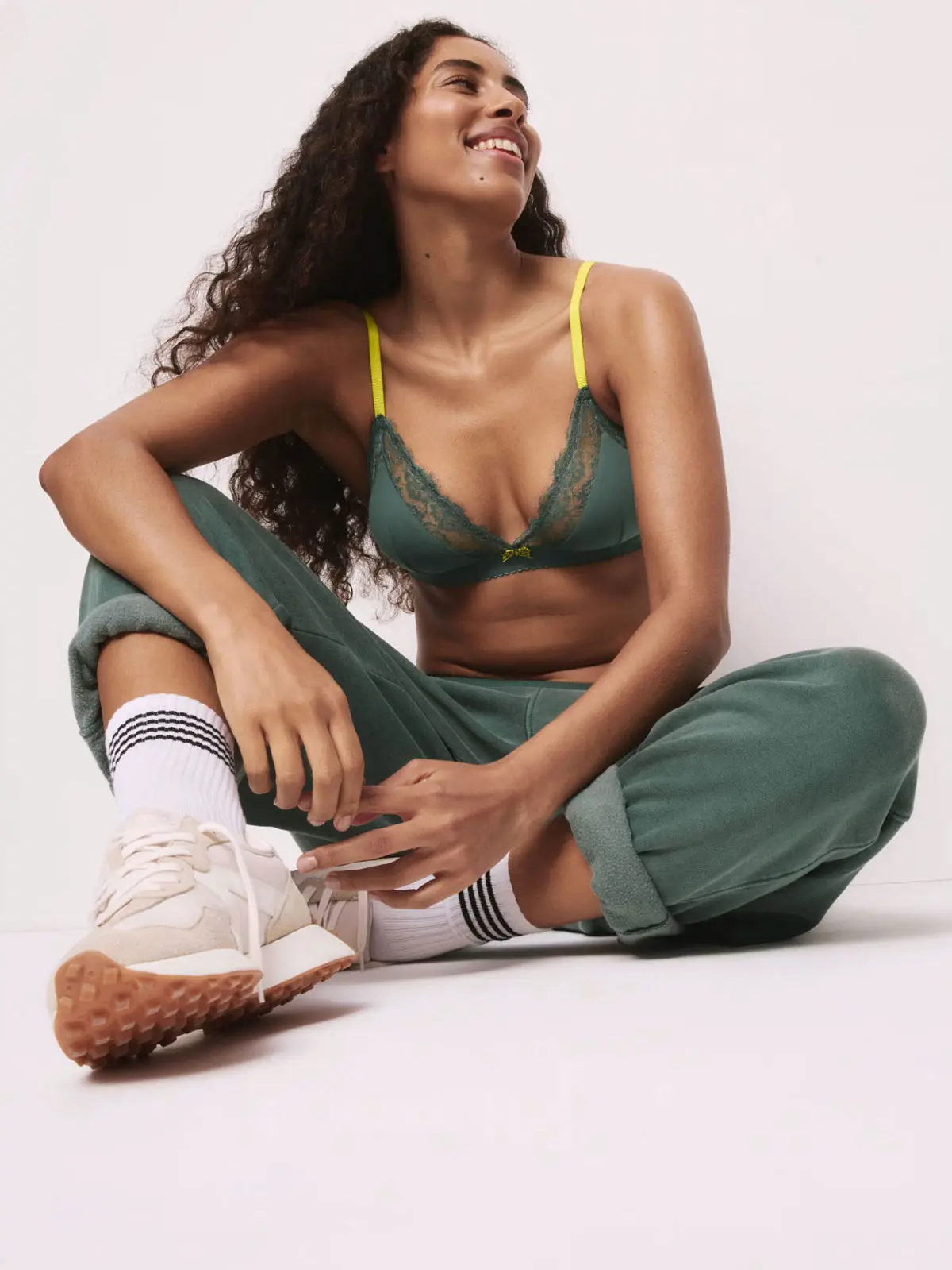 Woman wearing khaki green bra with contrasting straps, green trousers and white trainers