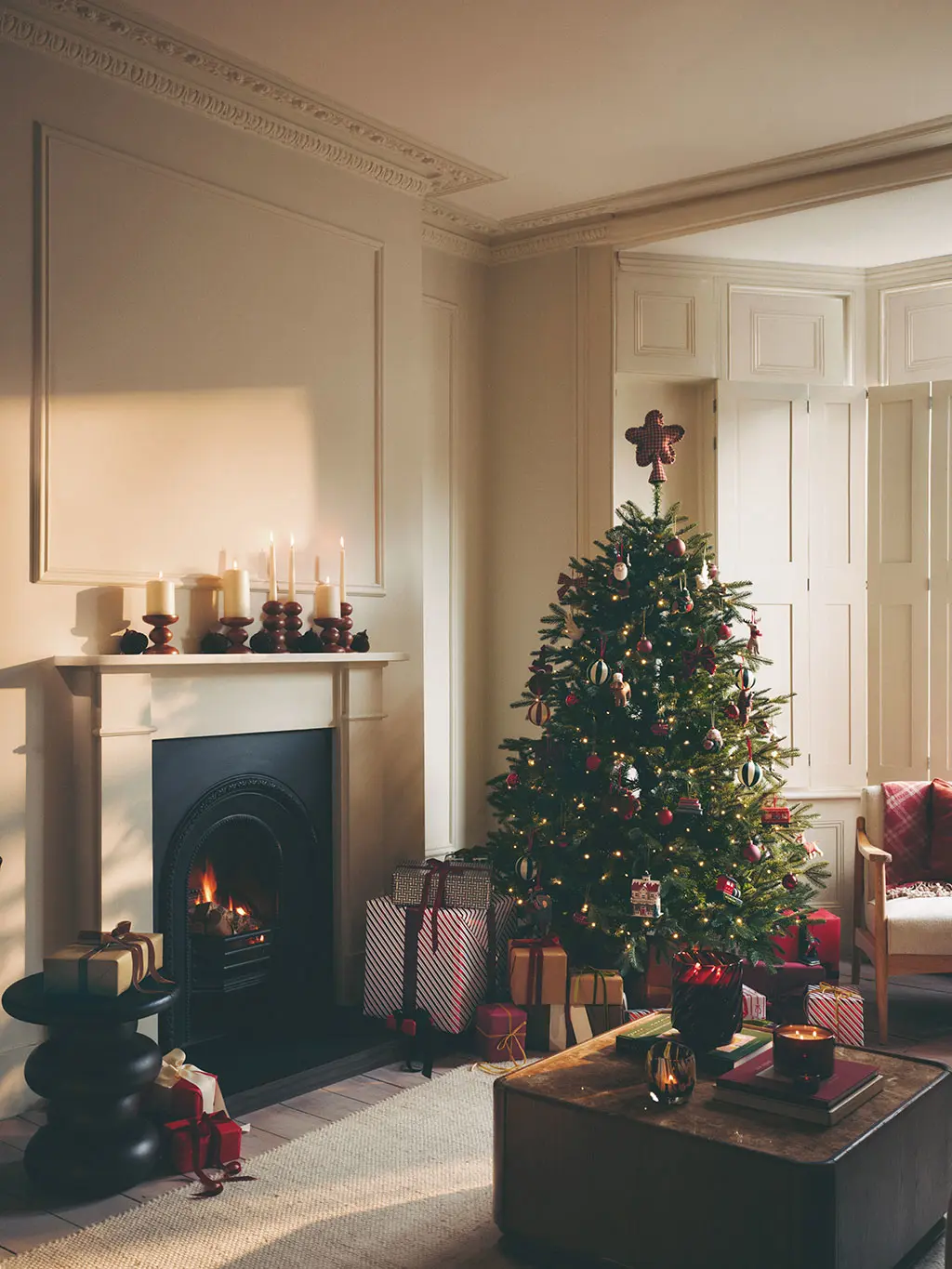 Cream room with a Christmas tree, fireplace and coffee table decorated with candles.