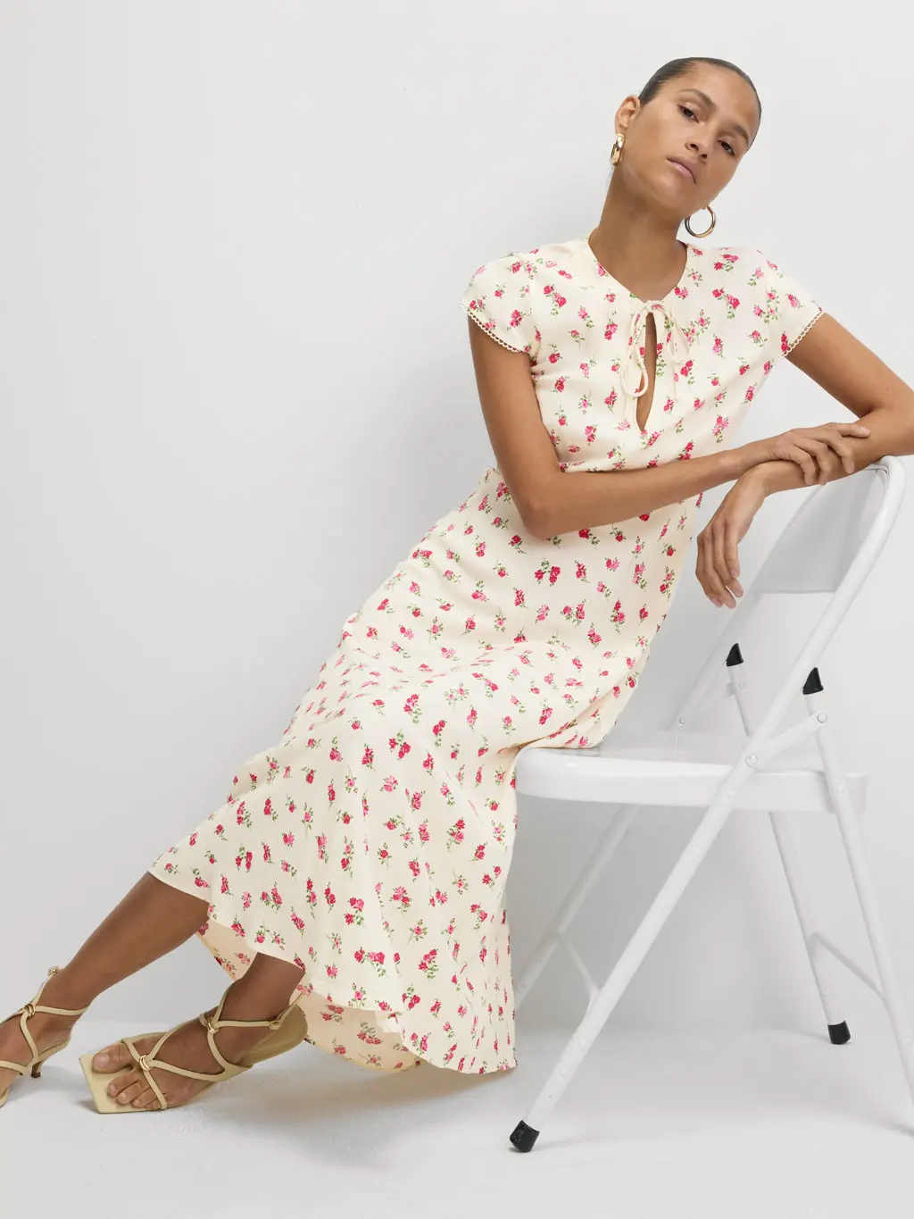 Woman wearing a floral print tea dress sat on a chair