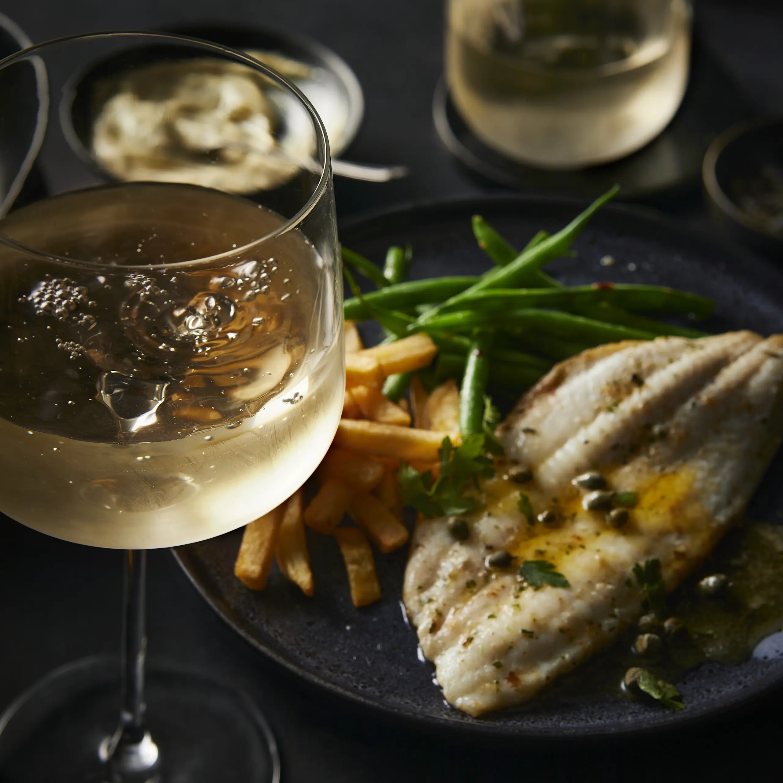 Glass of white wine and plate of fish with veggies