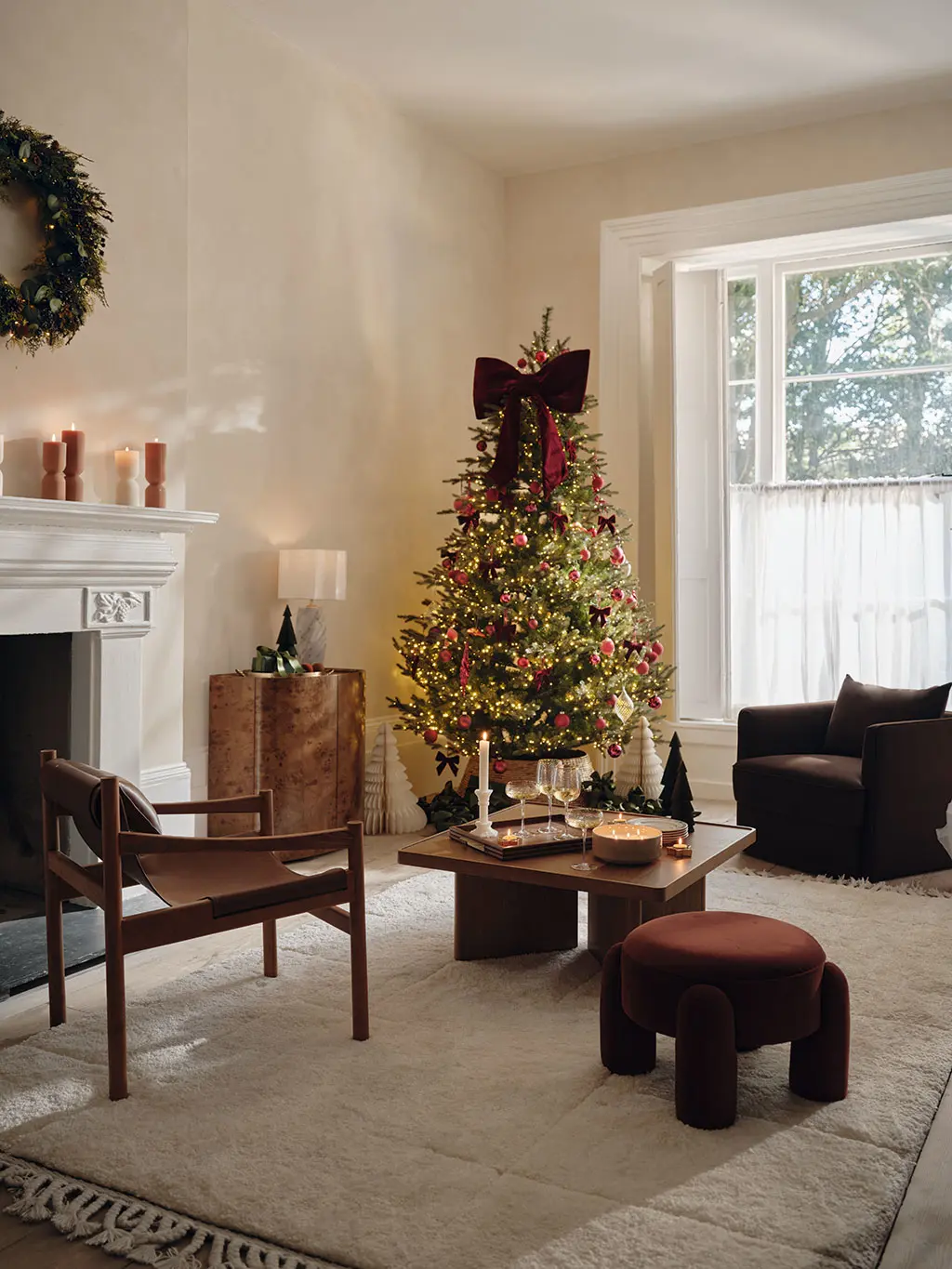 A cosy living room with a Christmas tree and a candles lit on the coffee table