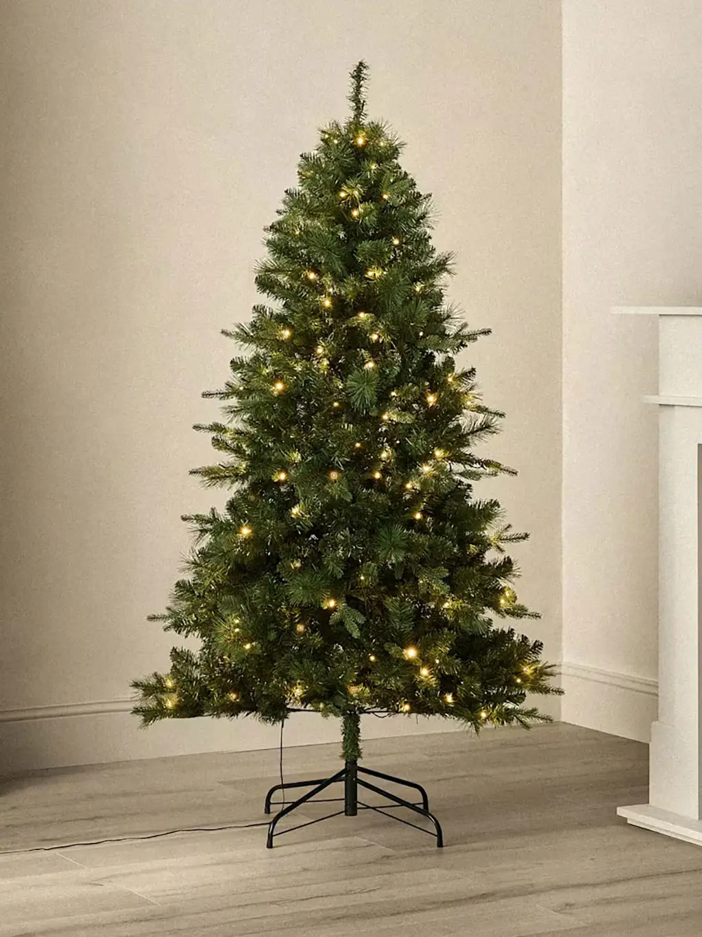 Artificial pine Christmas tree with warm white lights and metal stand.