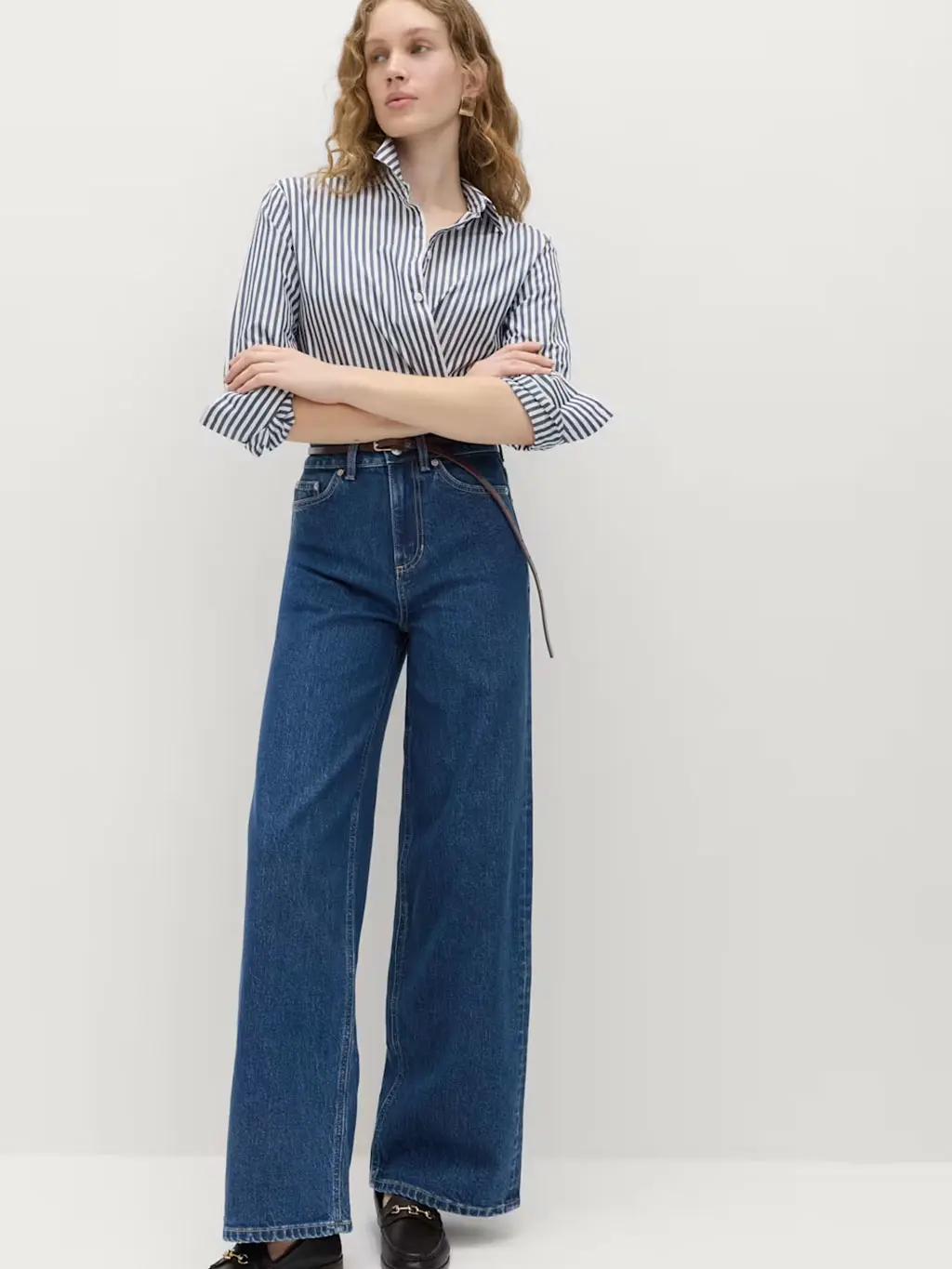 Woman wearing a striped shirt with blue indigo jeans and loafers
