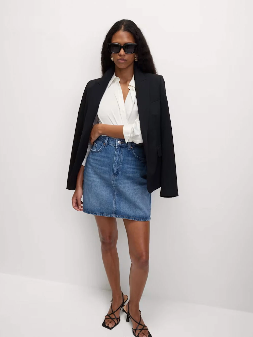 Woman wearing a black blazer, white shirt and denim mini skirt
