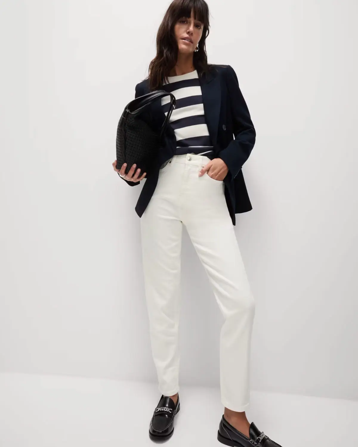 Woman wearing black jacket, striped top and white jeans