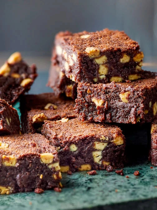 Brownie slices with white chocolate chunks stacked on top of each other on blue plate