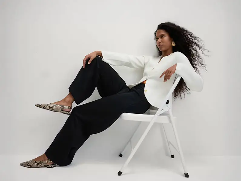 Woman wearing black trousers with a white shirt, animal-print pumps and a cross-body bag