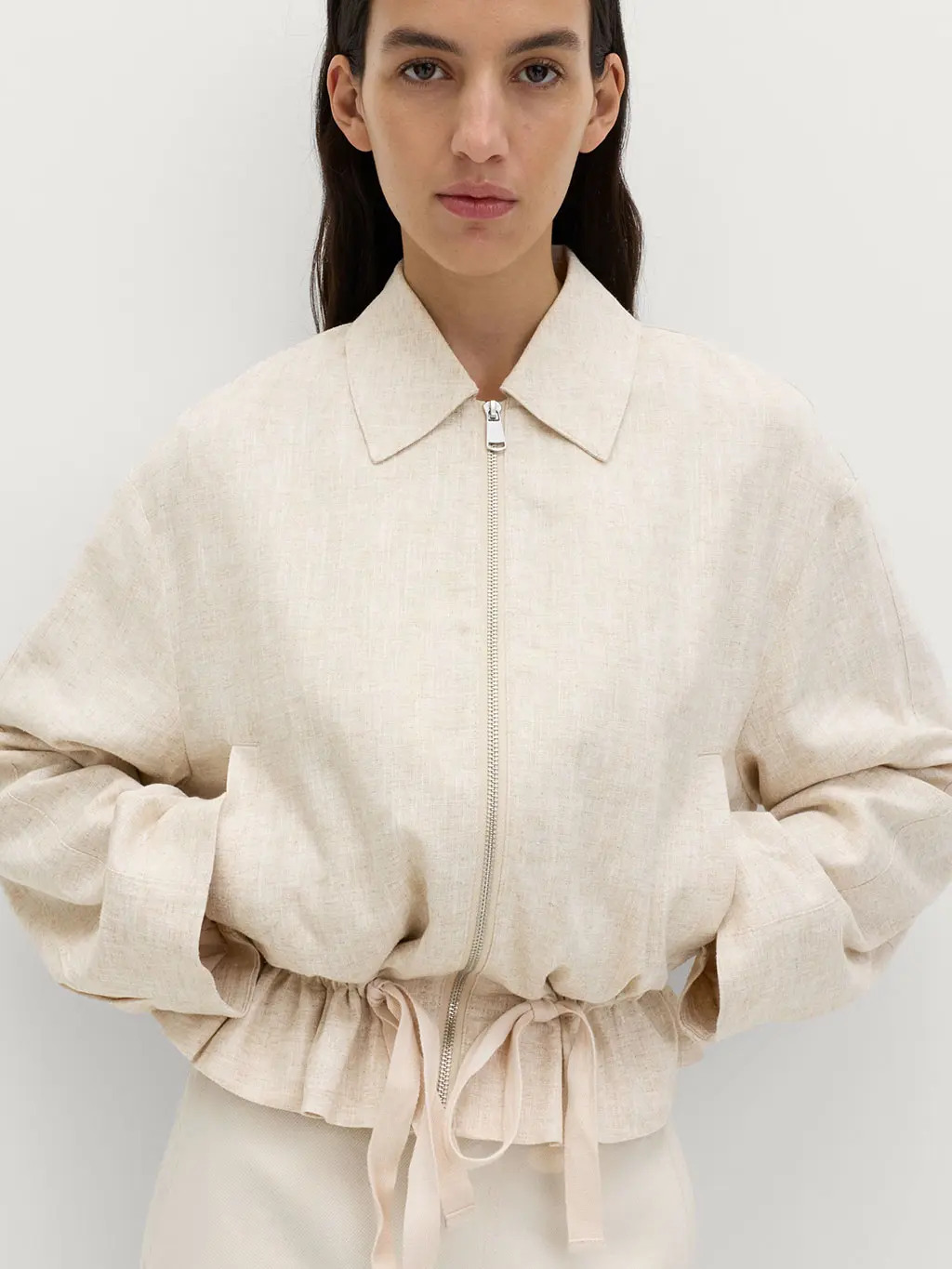 Woman wearing a neutral jacket with white trousers