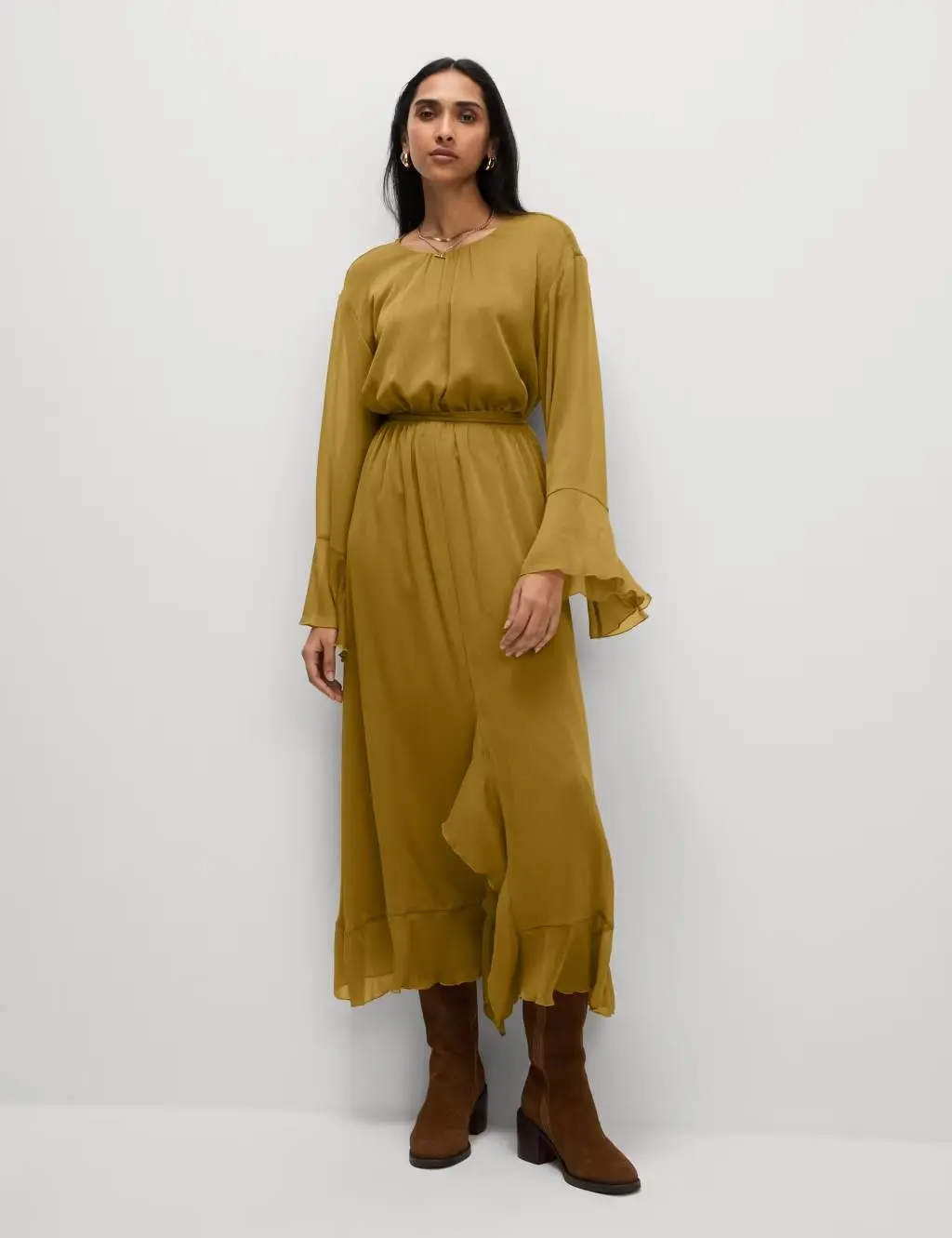 Woman wearing an olive frilled midi dress with brown suede boots