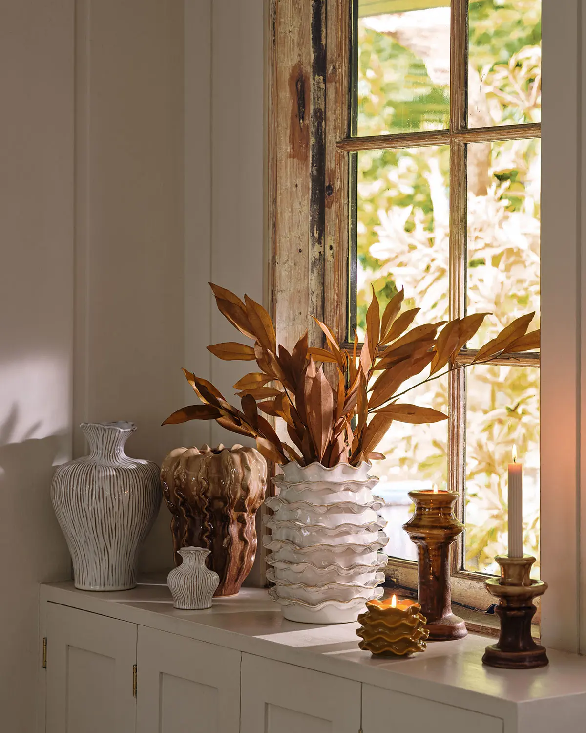 Windowsill with autumnal-themed vases and candlesticks