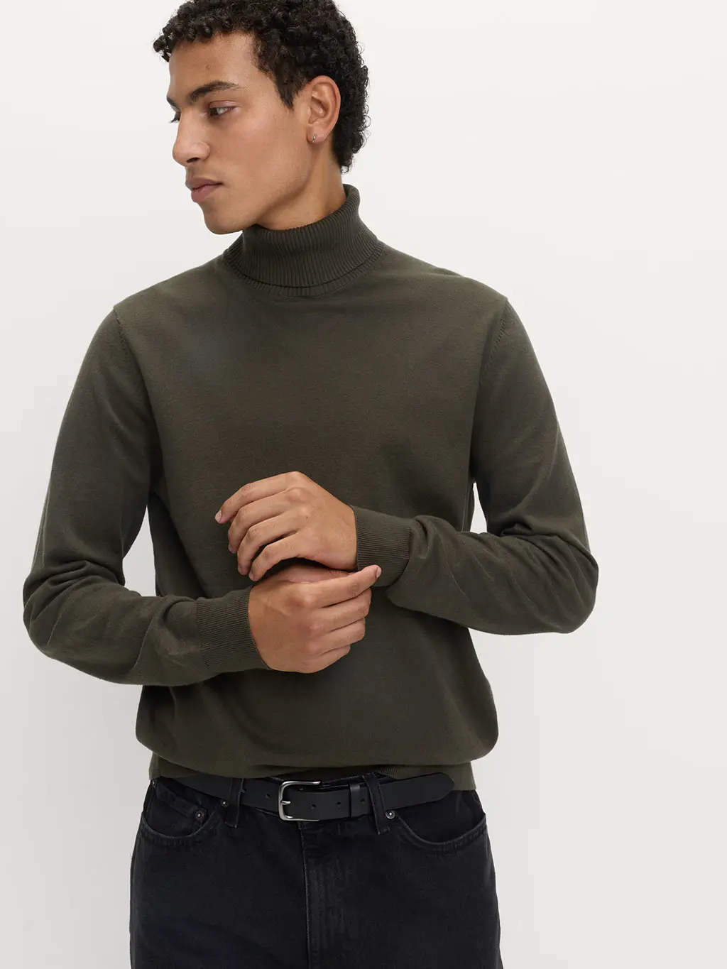 Man wearing green roll-neck jumper with black chinos and a black belt