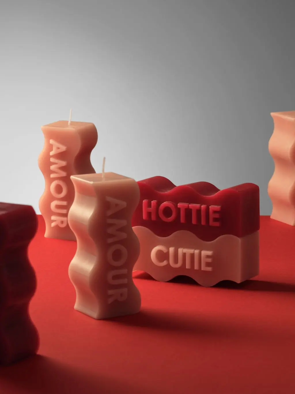 An array of candles saying hottie and cutie stood on a red table