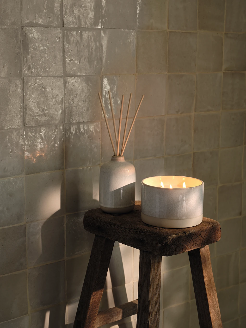 Scented candle and room diffuser on a stool in a bathroom
