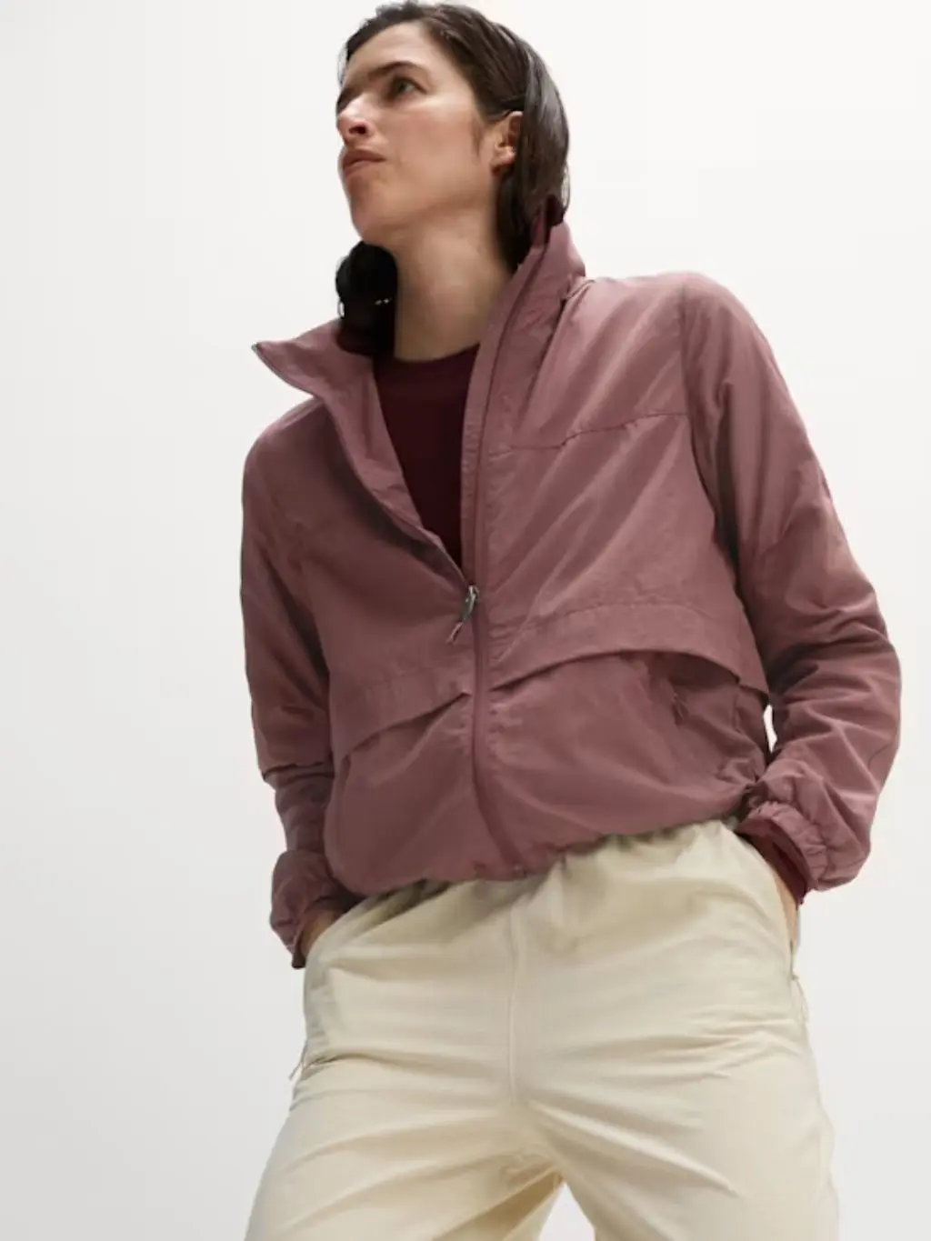 A woman wears a pink running jacket with cream bottoms