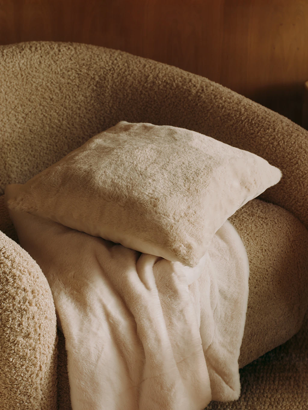 Boucle sofa with a faux fur throw and cushion.