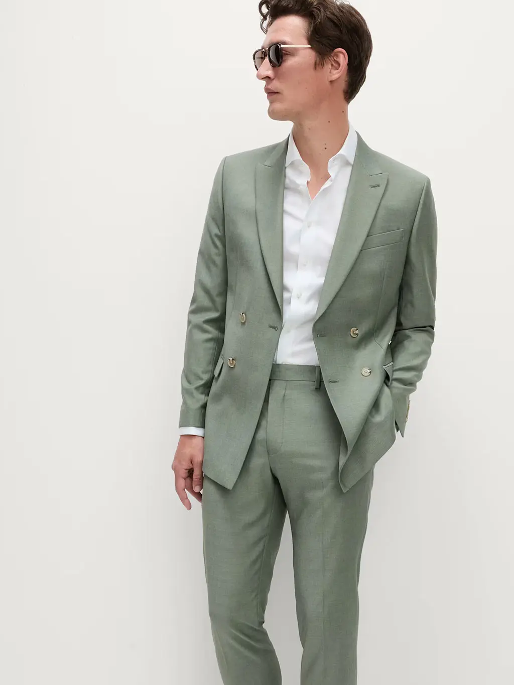 Man wearing a green double-breasted two-piece suit with a relaxed linen shirt and sunglasses