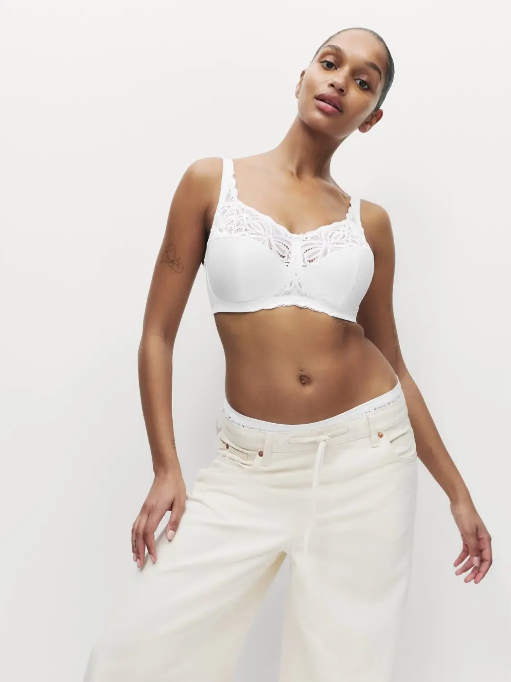 A woman wears a non-wired bra for a fuller bust with white jeans