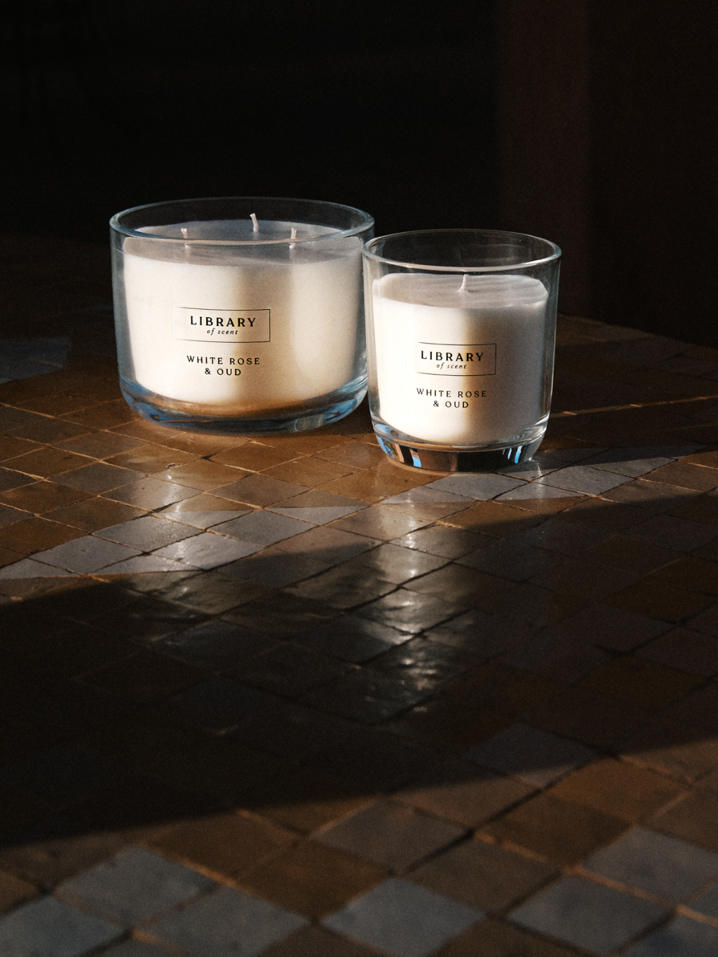 Two White rose and Oud candles shot on a tile floor