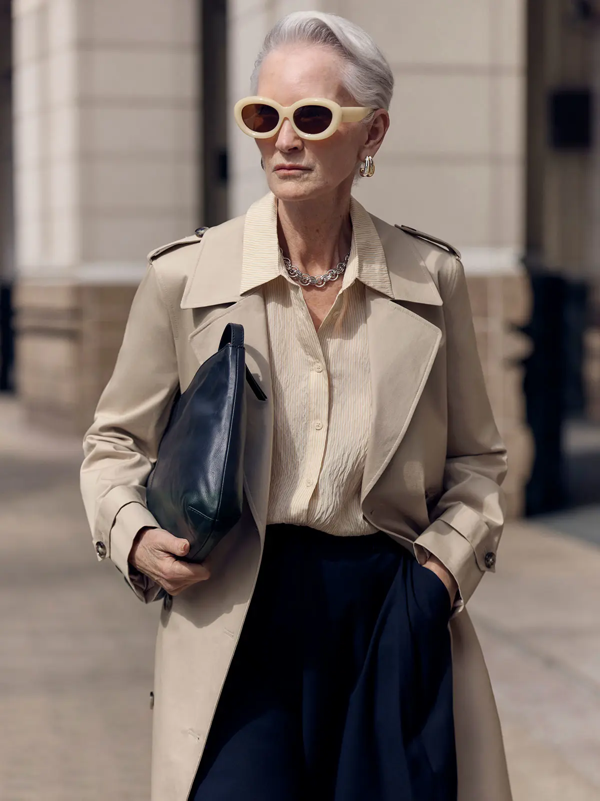 Woman wearing trench coat over shirt and navy trousers