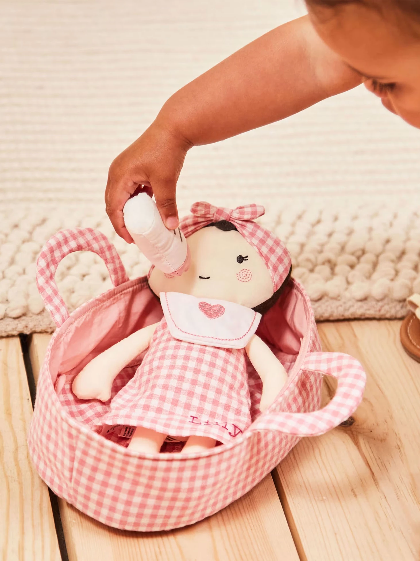 Personalisable doll wearing pink gingham dress in a pink gingham basket