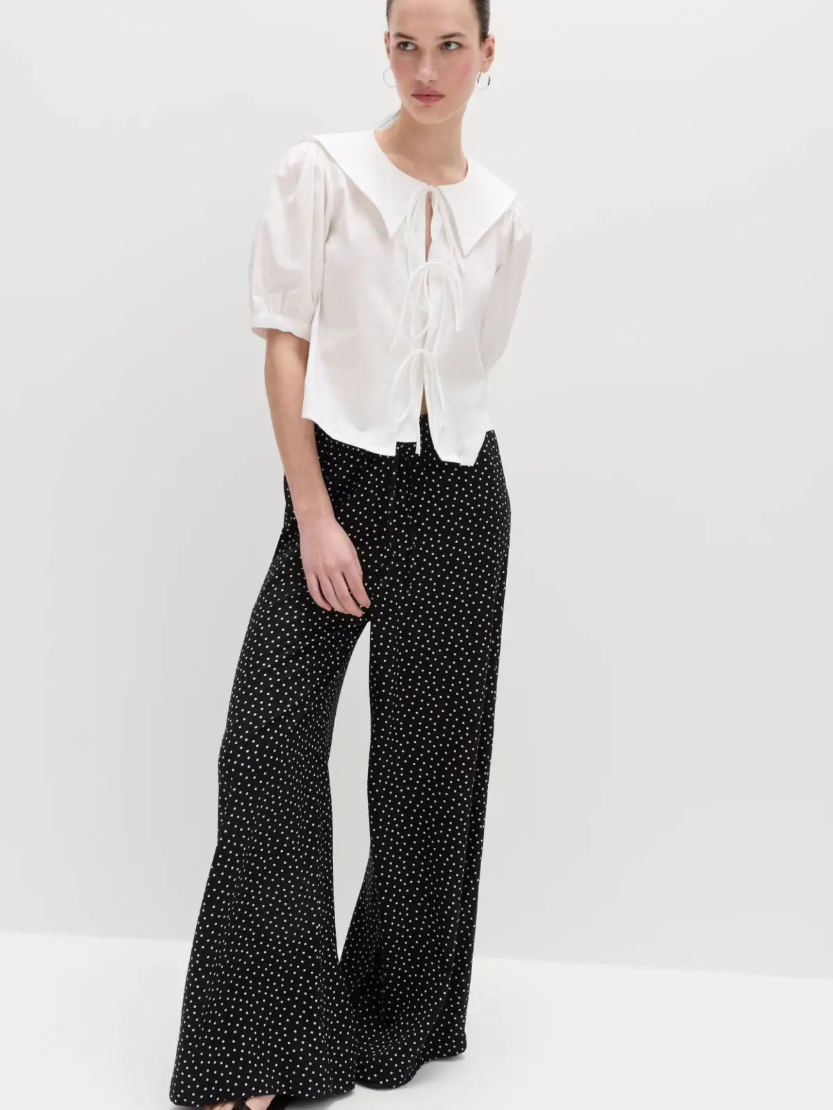 Woman wearing white collared blouse with polka-dot wide-leg trousers 