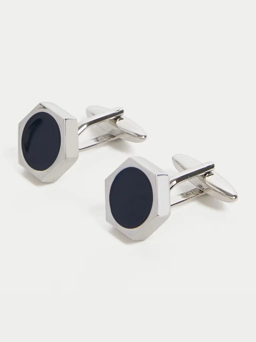 A cut out of silver and blue hexagonal cufflinks shot against a light background