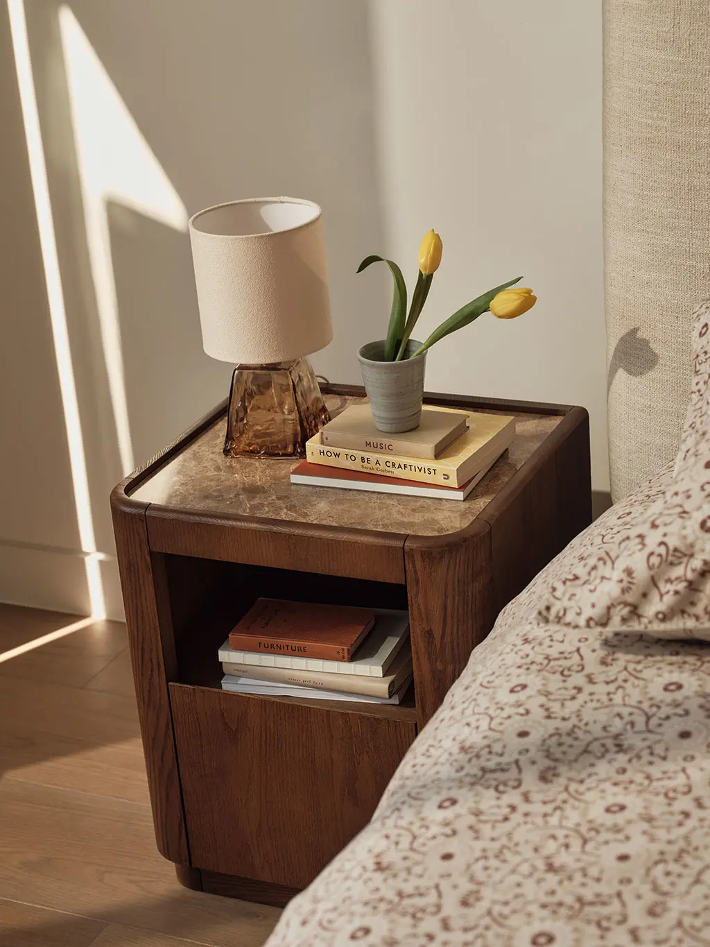 Bedside table with a glass lamp, flowers and a book
