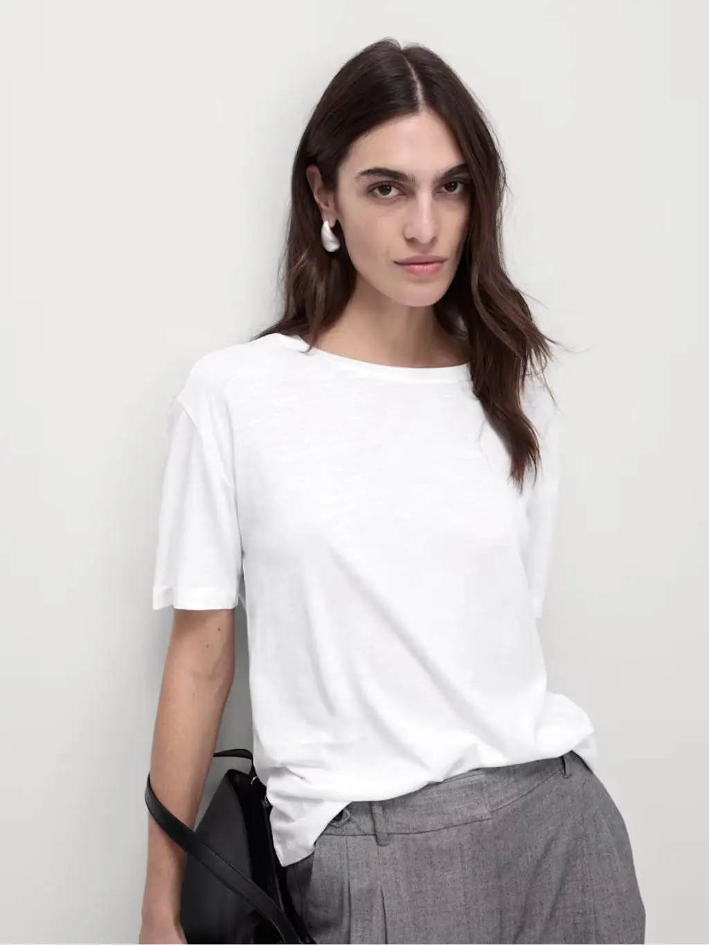 A woman wears a relaxed fit white tshirt with trousers