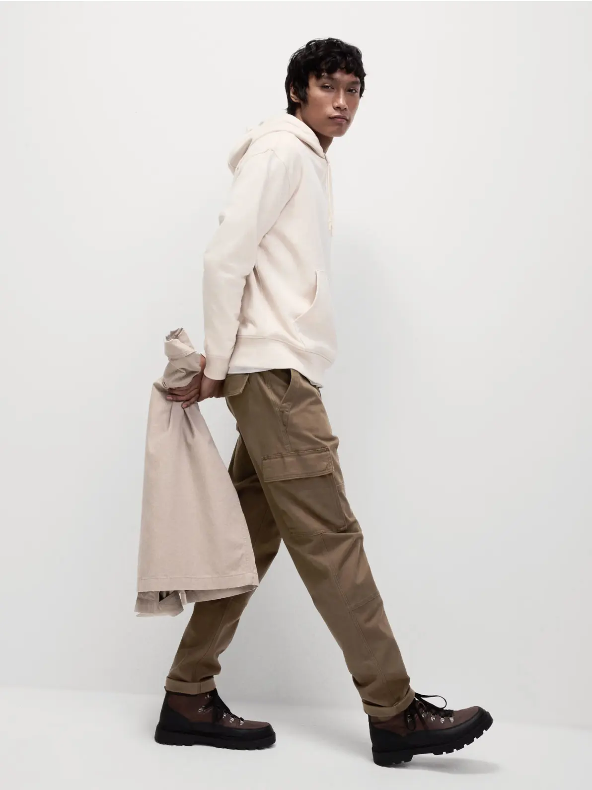 Man wearing cream hoodie, brown cargo trousers and walking boots 