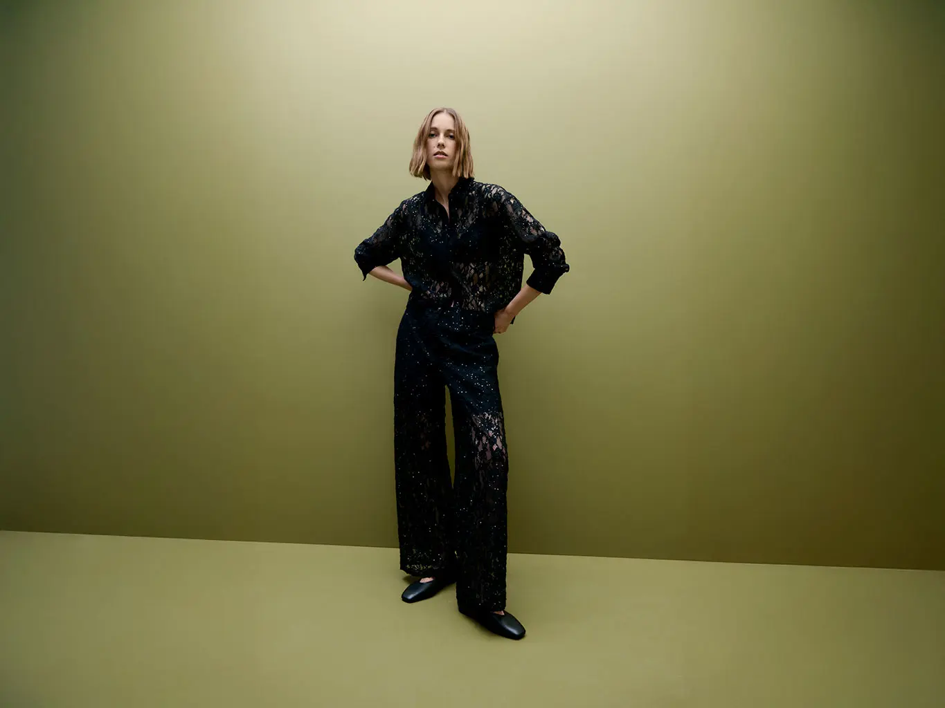 Woman wearing a lace shirt and trousers with black ballet pumps