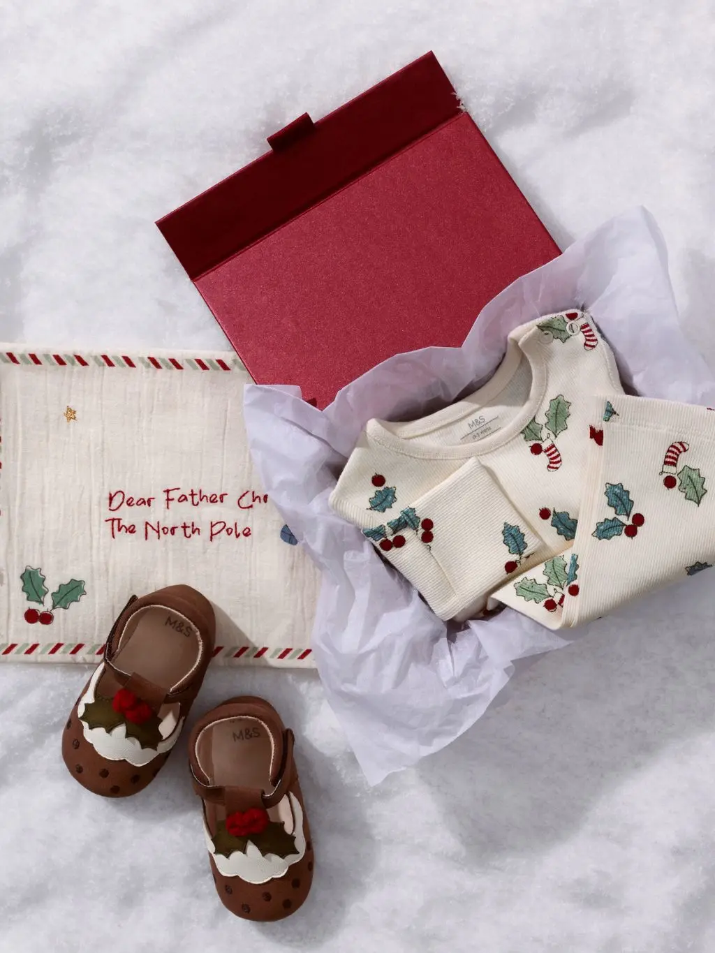 A gift box with Christmas pyjamas and slippers on the snow