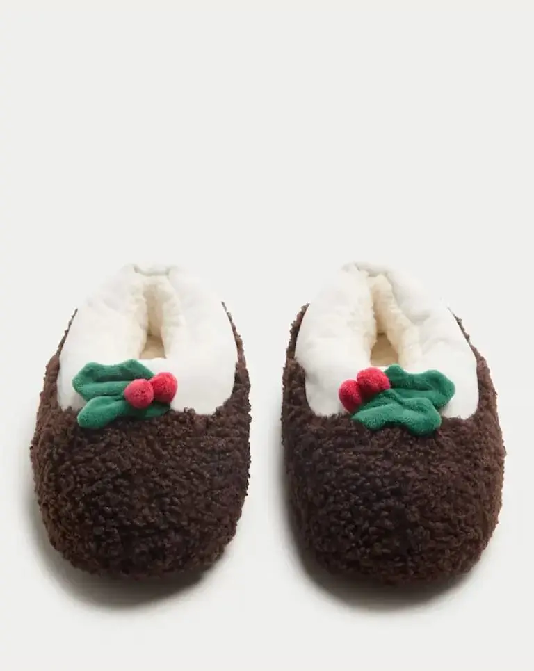 A cutout of baby Christmas pudding slippers on a pale background by M&S