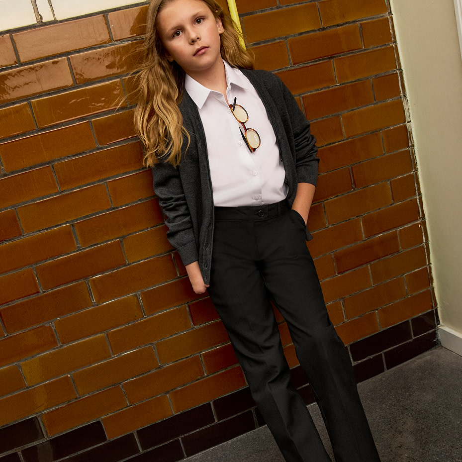 Child wearing M&S school uniform leaning on a wall