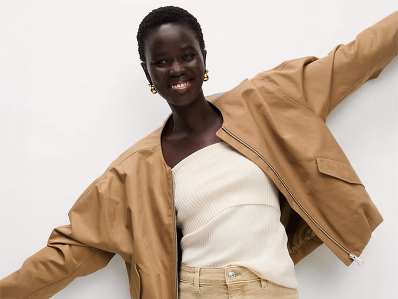 Woman wearing ochre bomber jacket, cream tube top and ecru wide-leg jeans