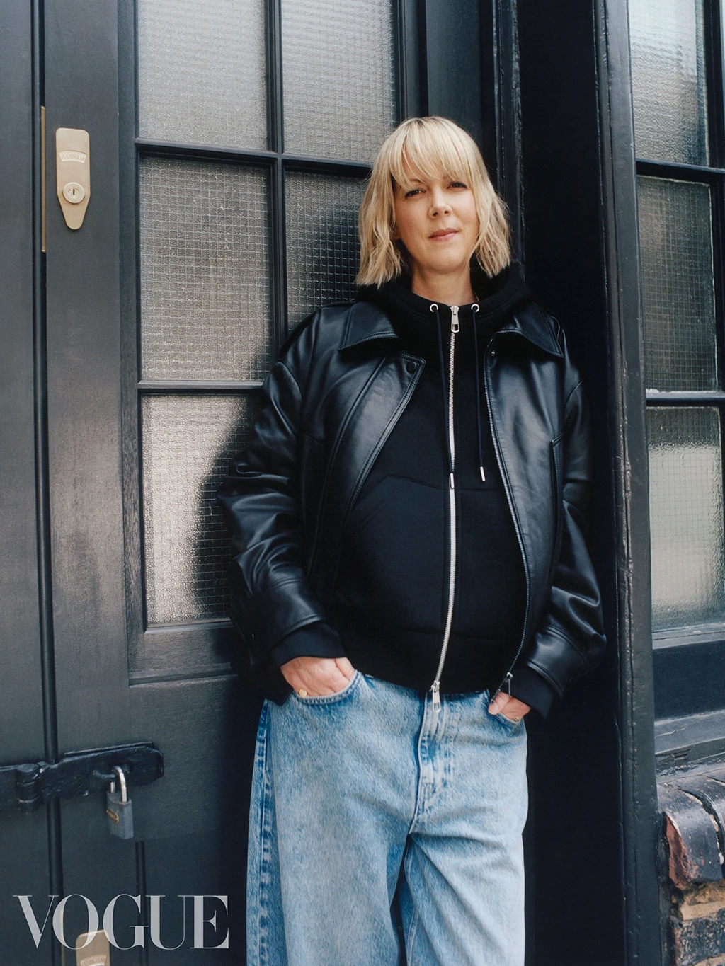 British Vogue editor Laura Ingham wearing a black leather bomber jacket, a black zipped hoodie and light blue jeans by Autograph