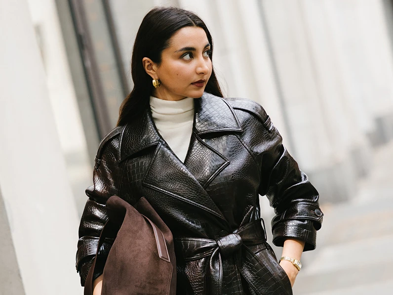 Marina Avraam wearing a dark brown mock-croc trench coat, white polo neck and brown bag