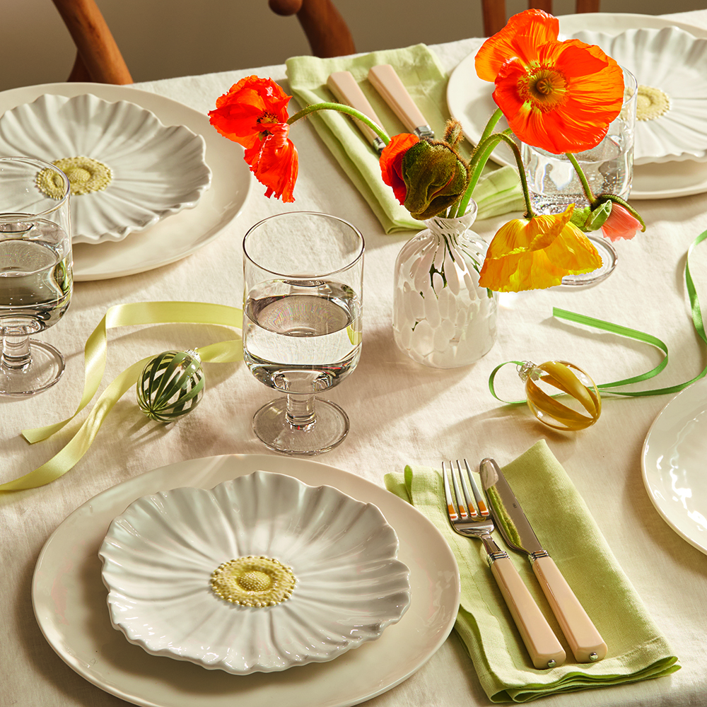 Table set with white tablecloth, floral-shaped crockery and orange poppies